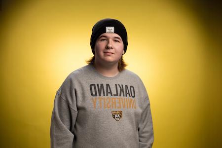 Jameson wearing an O U sweatshirt and beanie looks towards the camera smiling.